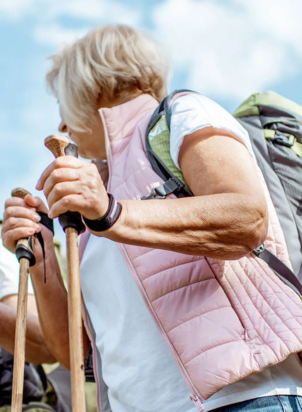 senior couple with backpacks and trekking poles enjoying nature on a sunny day