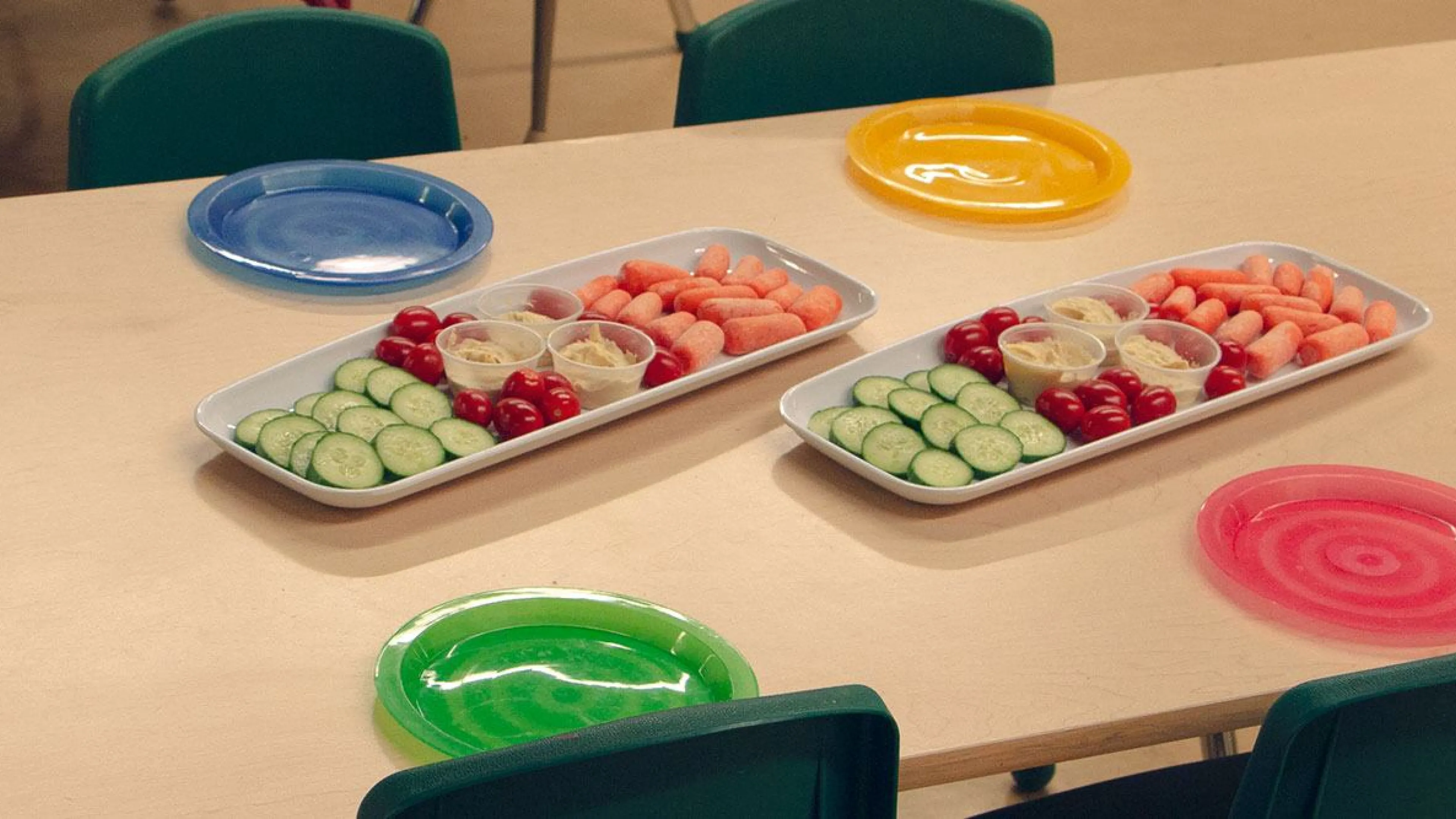 trays of vegetables and hummus surrounded by colourful plates and chairs