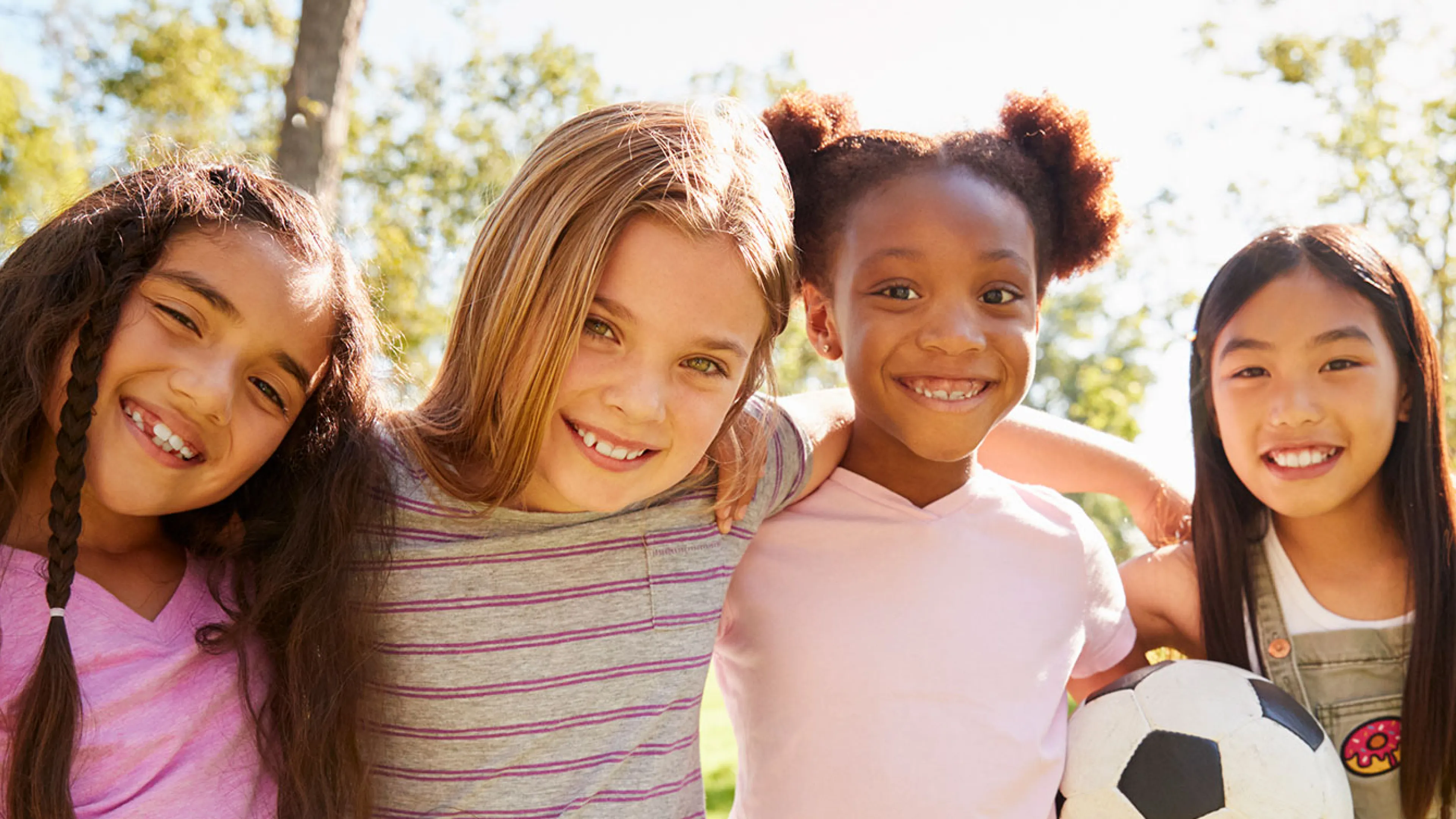 four happy girls outside with soccer ball