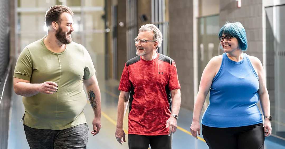 friendly young man, senior man, and middle aged woman enjoying a walk together on an indoor track
